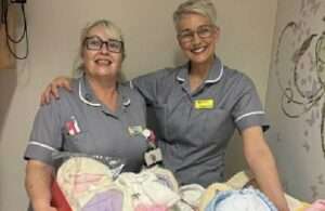 Two nurses in front of knitted baby items